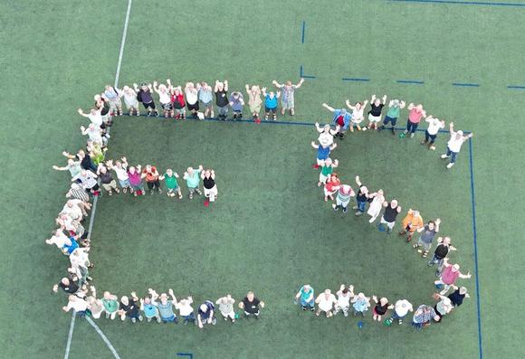 Drohnenfoto von einer Gruppe von Menschen, die auf einem Sportplatz die Buchstaben E und S für Energiegenossenschaft Starkenburg bilden.