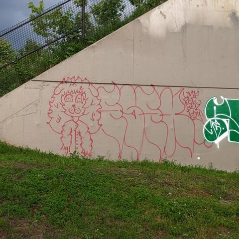 Large graffiti of a puppygirl/boy/creature with long curly hair next to some illegible graffiti (most likely an artist tag)
