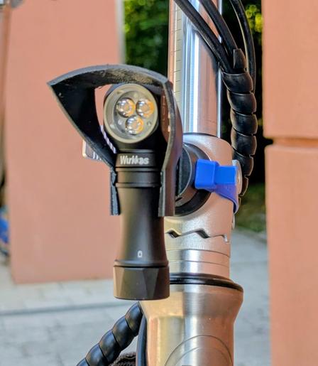 A wurkkos hd10 headlamp, mounted onto a vello folding bike with a custom 3dmodeled adapter system