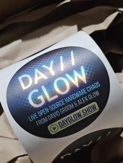 a roll of holographic stickers with the DAY//GLOW logo and dayglow.show web site