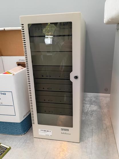 A Digital/DEC InfoTower, which is a big honkin' external SCSI enclosure. It has seven 5¼" drive bays behind a steel and smoked glass door in front, and SCSI output jacks in the back. This one has four identical CD-ROM drives in it. In this photo, the door is closed, and there's a $200 price tag on.