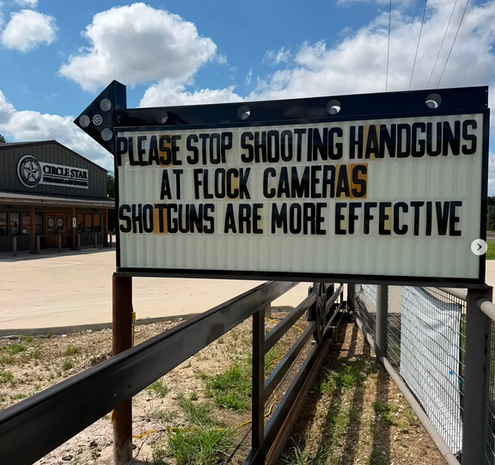 Outside Circle Star firearms in Houston, there is a sign that says "PLEASE STOP SHOOTING HANDGUNS AT FLOCK CAMERAS. SHOTGUNS ARE MORE EFFECTIVE."