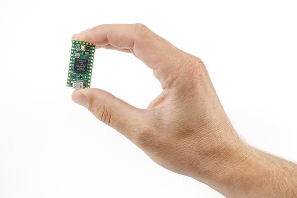 a Teensy 4.0 dev board being held between thumb and forefinger