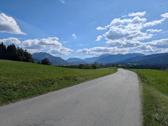 Blick von Niklasreuth Richtung Fischbachau und Bayrischzell unter weiß-blauem Himmel.