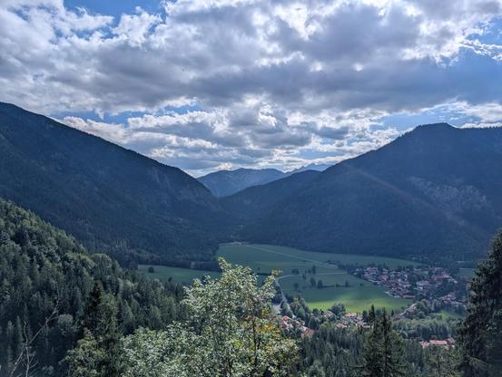 Blick von der Auffahrt zum Sudelfeld auf Bayrischzell unter weiß-blauem Himmel.