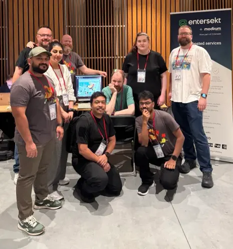 The Entersekt team posing for the camera (in front of an old computer with the EuroBSDCon website displayed), and the pull-up marketing banner to the right.