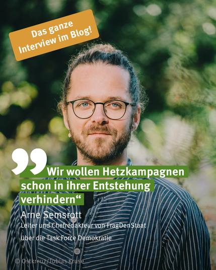 Porträt von Arne Semsrott, Leiter und Chefredakteur von FragDenStaat. Er steht vor einem unscharfen grünen Hintergrund und trägt eine runde Brille sowie ein dunkel gestreiftes Hemd. Auf dem Bild steht das Zitat: „Wir wollen Hetzkampagnen schon in ihrer Entstehung verhindern“. Darüber ein orangefarbenes Feld mit dem Hinweis „Das ganze Interview im Blog!“. Unter dem Zitat: „Arne Semsrott, Leiter und Chefredakteur von FragDenStaat, über die Task Force Demokratie“. Foto: Ostkreuz/Tobias Kruse.