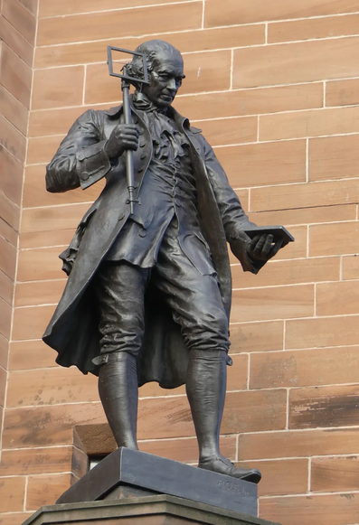 Statue of James Watt. In his right hand he holds a telescopic stick with a frame at the top; in his left he holds a flat object about the size of a large smartphone. He is scowling at the possibly-not-a-smartphone as if he is tempted to yeet it into the sea. On that basis, it probably _is_ a phone.