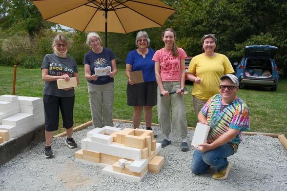 Happy kiln builders standing around the base of a rocket kiln.