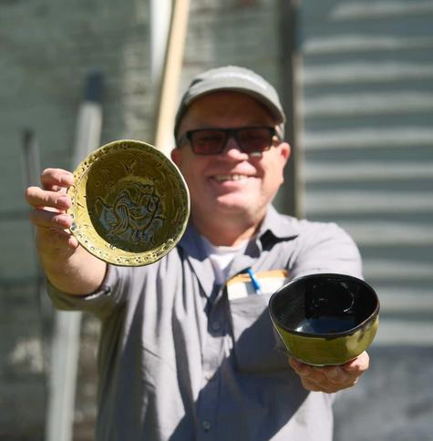ken with a big grin holding a couple of his pots...