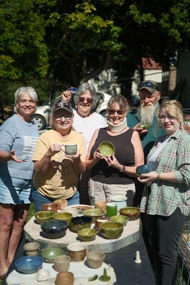 a photo of a group of potters holding some of their newly fired pottery