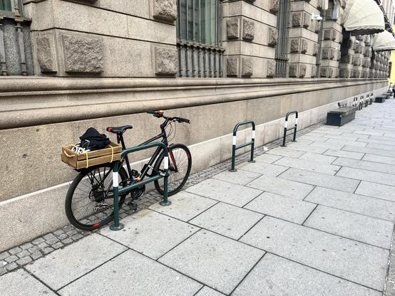 A photo of Matt’s bike at the end of the working day, locked to a bike rack in front of a fancy building.