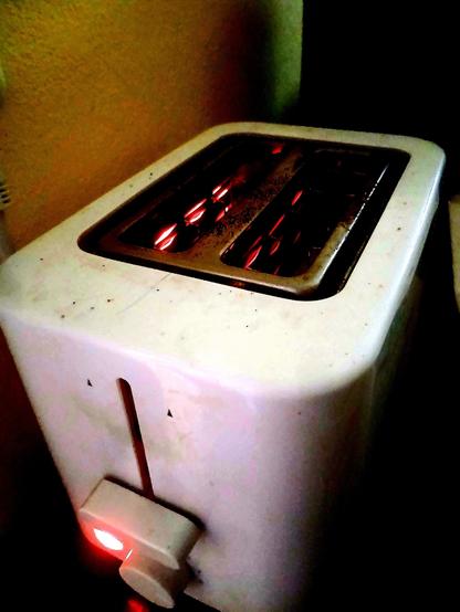 Filaments glow red as toast toasts in the toaster, round side down.
