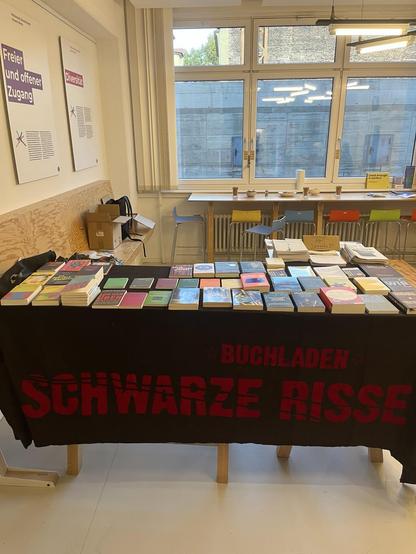 Büchertisch mit vielen Büchern und einem Banner mit der Aufschrift "Buchladen Schwarze Risse"