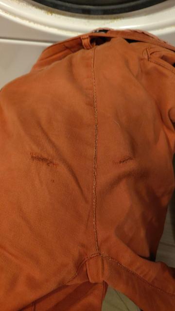 A pair of redish shorts with mirrored wear holes where your sit bones would lie while seated.