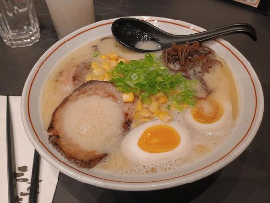 A bowl of tasty soup with egg, pork, corn and noodles therein