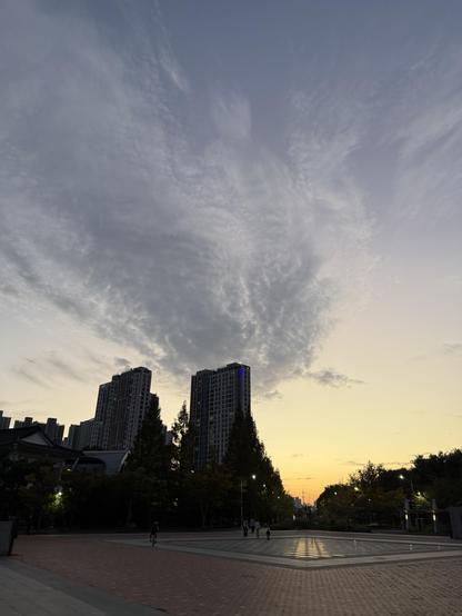 Dusk; thin wispy clouds across the center left almost like smoke from the 2 high rise towers across the plaza
