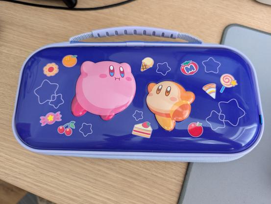Photo of a HORI Kirby case for Nintendo Switch 2 in a purple colour and lilac handle featuring Kirby and Waddle Dee.