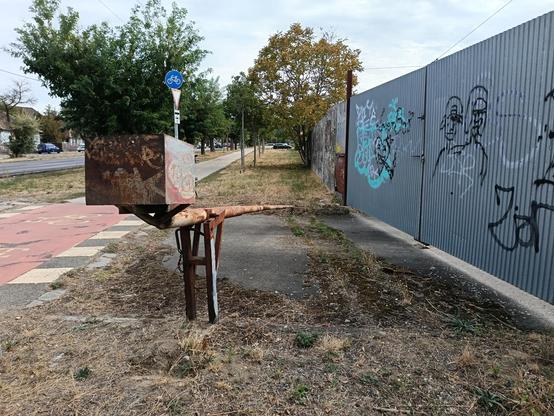 Abandoned barrier on a road barricated via metal fence.