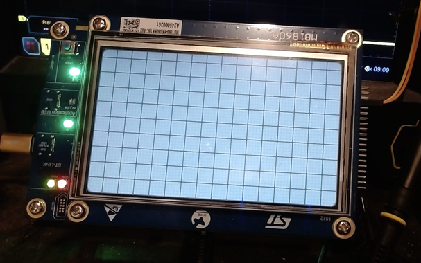 Picture of an LCD Display on an STM32U5G9-DK2 project board displaying "graph paper" (a sort of quadrule design) at a low enough intensity that the auto-brightness of the Webcam taking the picture can focus and resolve the display clearly.