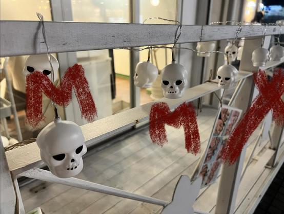 A photograph of little white plastic skulls attached to a fence.