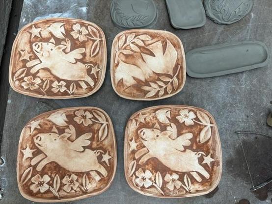 A group of small rectangle shaped plates. They are decorated with flying pigs and doves with peace aymbols
