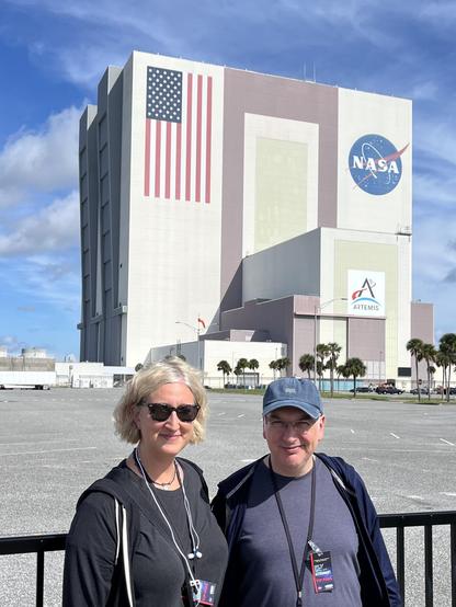Myself and Jessica smiling in the Florida sunshine in front of the humongous block building painted with an enormous stars'n'stripes and a NASA meatball logo.