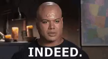 a bald man with a medallion on his forehead is standing in front of candles and says indeed .