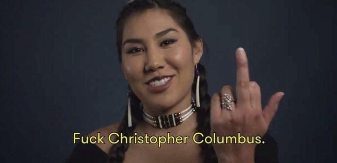 Photo of a Native American woman giving the middle finger with a smile with the caption underneath: "Fuck Christopher Columbus."