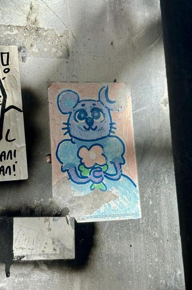 A sticker on a street sign with a drawing of a cute mouse lady