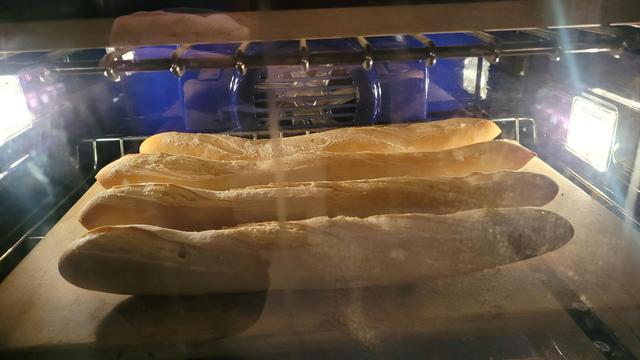 Baguettes halfway through baking in an oven at 230C with steam.