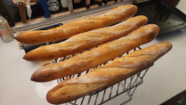 Baguettes cooling down on a wire rack after being pulled from the oven.