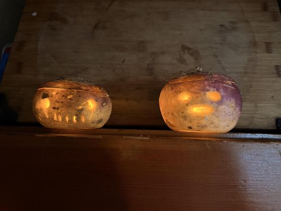 Two turnips with glowing faces carved into them. The faces are very simple.