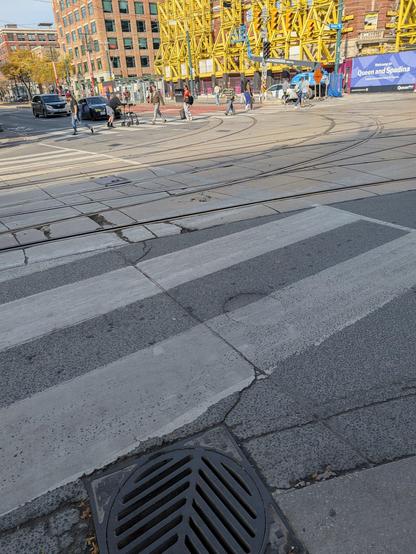 A shot looking northeast across the Queen/Spadina street intersection, with the offending storm grate cover visible in the immediate foreground.