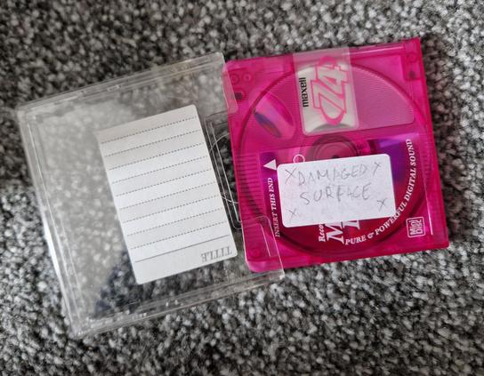 A photo of a rewritable mini disc labelled "x x damaged surface x x"