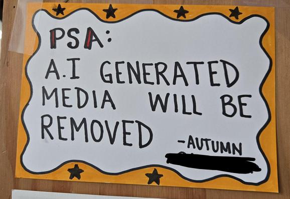 little hand drawn sign that reads PSA: AI generated media will be removed -Autumn (and the name of the cafe is scribbled out)
