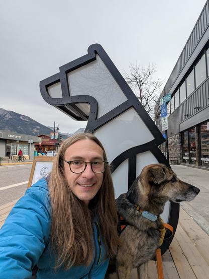 A selfie of me and my dog in front of a bear statue with a mountain in the background