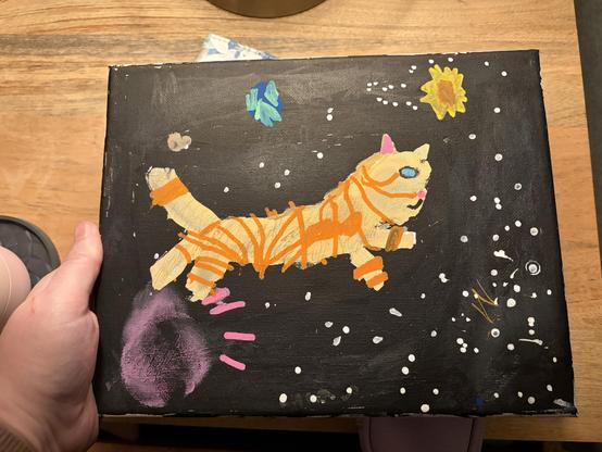 A child’s painting of an orange striped cat in space