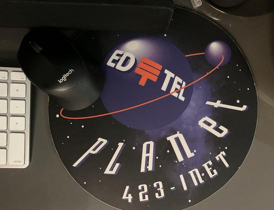 A massively oversized circular mousepad. It has the EdTel (Edmonton Telephones) logo on the front, on a planetary body. It reads: PLAnet, 423-INET.