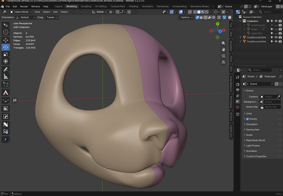 A interface for the 3D program Blender, showing various default menus and buttons, with the main image in the 3D viewport of a solid feline mask with large holes for eyes.  It is split down the horizontal center into two halves, one of which is a gum pink and the other of a light tan.