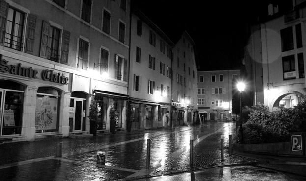 regennasse Strasse in einer Altstadt mit einigen Strassenlaternen die sich auf der nassen Strasse spiegeln