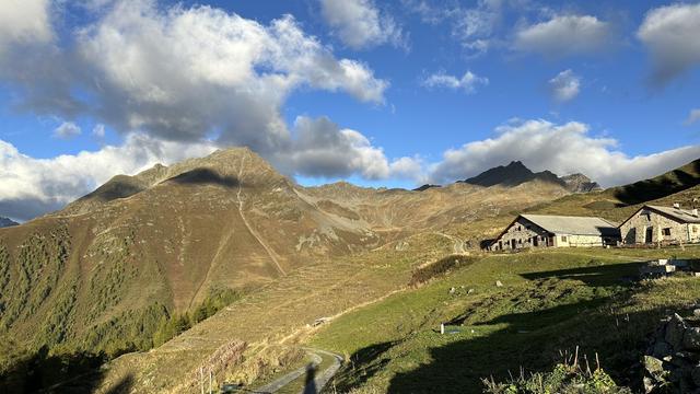 View of Piz Chapisun on the opposite side of the Val Tuoi with the pastured hillsides and farm buildings of Alp Sura (2,118 m) in the right foreground.