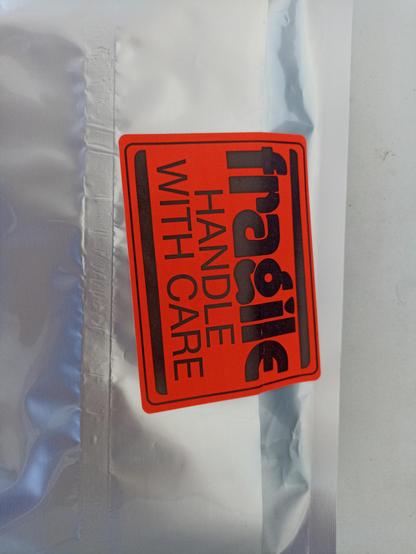 "Fragile - handle with care" sticker on an electronics components antistatic bag. The word "fragile" is written in an unusual fantasy font, with a 1970s feeling to it (I hope someone better at fonts than me can describe it better)