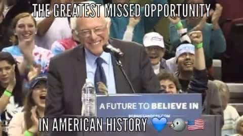 Man speaking at a rally with excited crowd, holding a sign that reads "A FUTURE TO BELIEVE IN," in front of a microphone.