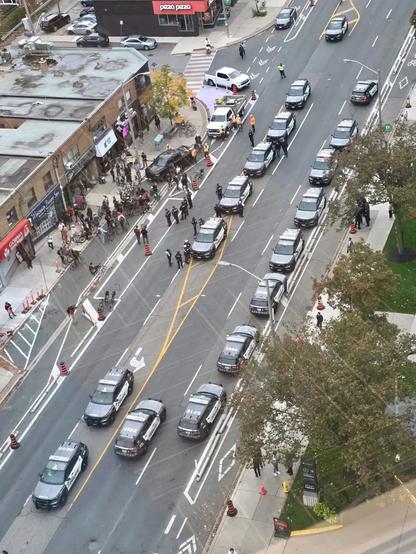 Photo from above (drone or high-rise) showing over a dozen police cars near Bloor & Islington