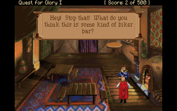 A screenshot from Quest for Glory I: So You Want To Be a Hero. A hero character stands proudly in a faux tudor-style inn, with a katta (cat) cleaning himself. The mouth verb has been used on a fireplace burning warmly in the corner.
