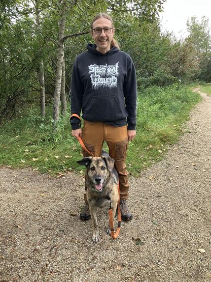 picture of me and my dog. I'm wearing a black spectral wound hoodie and orange pants and my dog is sitting between my leg looking at the camera with her mouth open