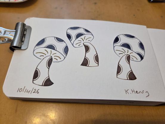 Hand drawn generative/procedural art in ink on an open page of my sketchbook. The abstract pattern looks like mushrooms with polka dots on their stems and caps. A metal binder clip holds my sketchbook open.