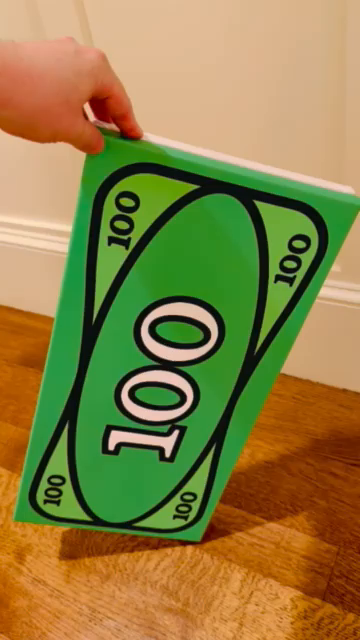 a rectangular canvas print of brick 100 dollar bill, and "THIS IS YOUR GOD" in greyscale brick font ala They Live, mounted so each one faces outward, back to back. Placed downward, balanced on edge, rotating with hand so each side is shown as it turns.