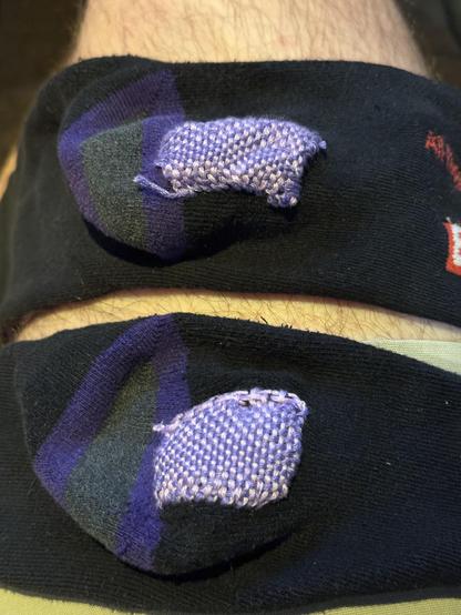 The heels of two socks. They both have woven patches in shades I’d purple.